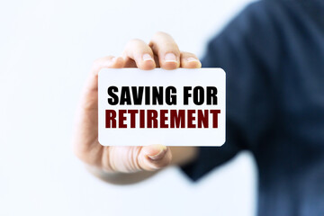 Saving for retirement text on blank business card being held by a woman's hand with blurred background. Business concept about retirement saving.