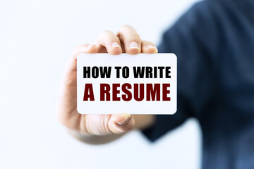 How to write a resume text on blank business card being held by a woman's hand with blurred background. Business concept about writing resume.