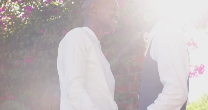 African american gay male couple holding hands and looking at each other at wedding, slow motion