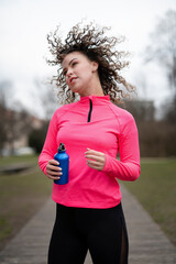 young stylish woman with a bottle of water doing sports outdoors