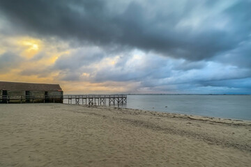 Fototapeta premium Empty wooden pier with dramatic sky and calm water