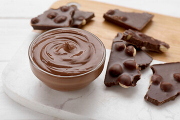 Bowl with tasty paste and pieces of chocolate on white wooden table, closeup