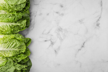 Fresh green romaine lettuces on white marble table, flat lay. Space for text