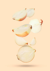 Cut fresh onions falling on beige background