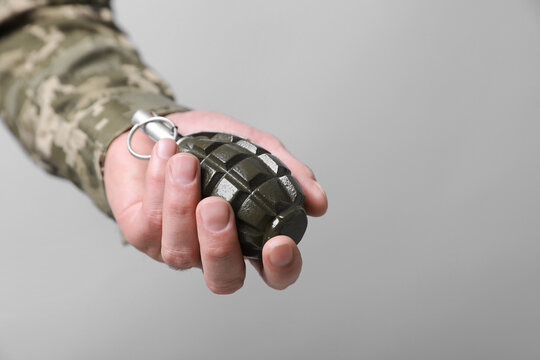 Soldier holding hand grenade on light grey background, closeup with space for text. Military service