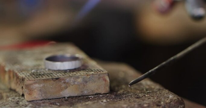 Close up of shaping ring with blowtorch in workshop in slow motion