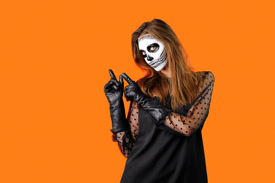 Young beautiful European female wearing casual clothing, defocused, holding orange pumpkin in her hands close-up on gray background. Halloween party concept.