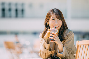 テラス席でコーヒーを飲む笑顔の日本人女性 - obrazy, fototapety, plakaty
