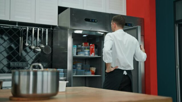 professional kitchen chef looks into the fridge and chooses ingredients for cooking food concept