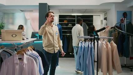 Store manager working with augmented reality hologram in shopping center, looking at modern trendy clothes on hangers. Retail worker using artificial intelligence in boutique, small business.