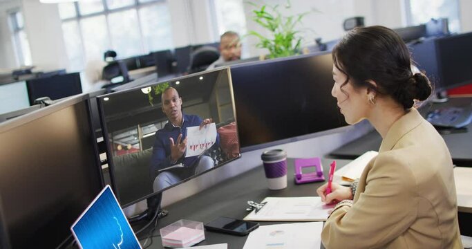 Asian businesswoman in office using computer with video call and ai messaging on screens