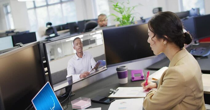 Asian businesswoman in office using computer with video call and ai messaging on screens
