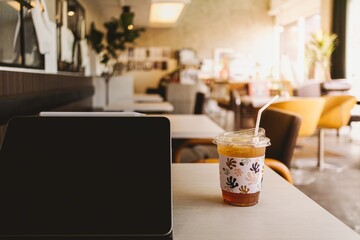 Tablet and a cup of iced coffee in the cafe. Concept of working in the cafe.