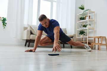 Obraz premium Man sportsman training at home, stretching exercises for arm, leg and back muscles, strong body and correct posture, the concept of health and beauty