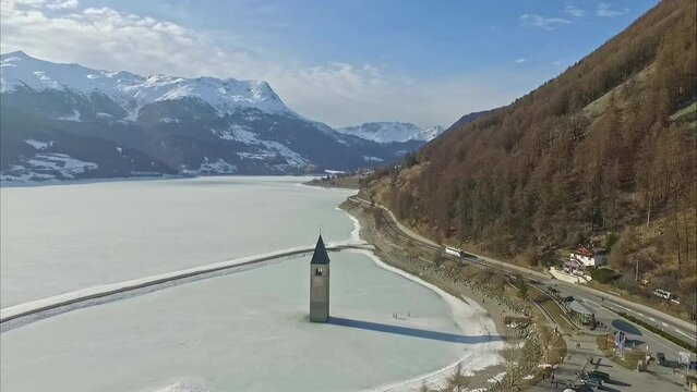 Aerial Drone View Of Frozen Lake Reschensee With Sunken Parish Church Steeple In South-Tirol, Italy. 