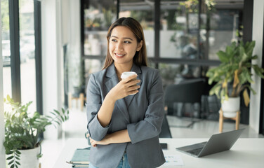 Asian businesswoman smiling happily with a new morning holding a cup of coffee lightly sipping...