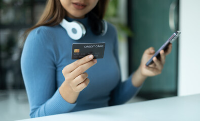 Asian girl shopping online holding credit and using smartphone enter their card number in the mobile phone app to purchase and payment in internet store