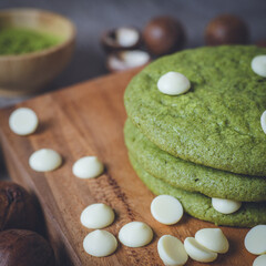 Matcha cookies with macadamia nuts and white chocolate chips on a dark wooden table