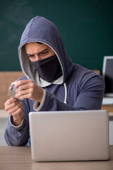 Young male hacker sitting in the classroom
