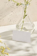 Realistic mock up name card. Empty paper card in natural realistic style. mock up card with shadows flowers and beige background. Light esthetic composition for design. Sunny Template blank.