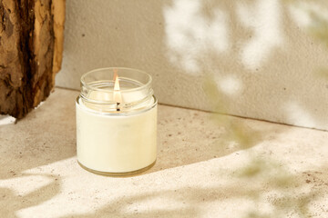 Simple composition with aromatic burning candle in jar. Mockup soy wax candle with wick in natural...