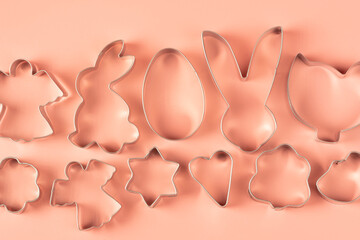 Baking kitchen utensils with easter cookie cutters on pink background, top view
