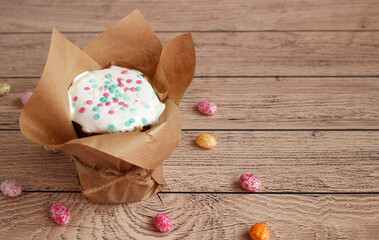 Easter cake in brown shape in white glaze sprinkled on a wooden background