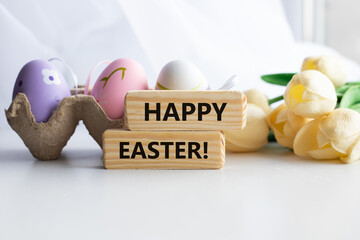 Colorful decorative eggs and HAPPY EASTER text close-up, against the background of a white flowers