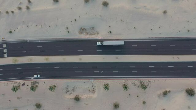 Aerial drone top down view of a semi truck with a long trailer traveling on a paved road.