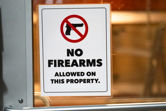 Close up of No firearms allowed on property sign in store window banning gun of private property.