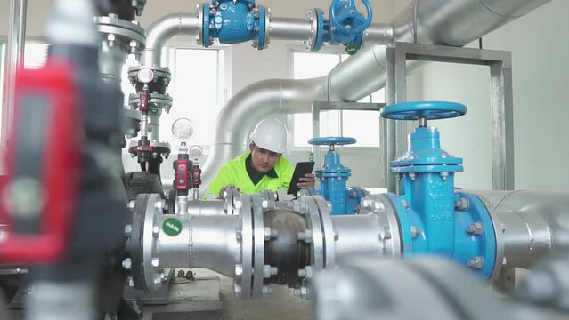 
A engineering at  inspects water pump valves equipment in a substation for the distribution of clean water at a large industrial estate. Water pipes. Industrial plumbing. Slow motion Shot.