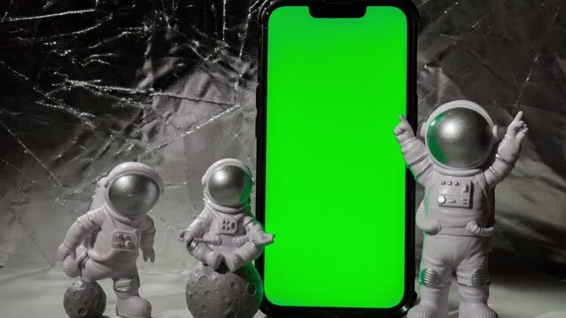 Stop motion Plastic toy figure astronaut with mobile phone chroma key green screen for your advertisement Copy space. Concept of out of earth travel, private spaceman commercial flights. Space