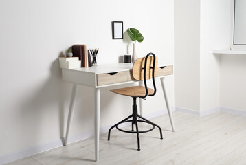 Comfortable workplace with white desk near wall indoors