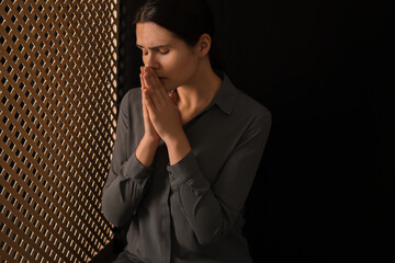 Woman praying to God during confession in booth