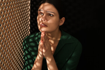 Woman praying to God during confession in booth