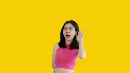 Asian woman eavesdropping or overhearing secret conversation isolated on yellow background, Gossip,...