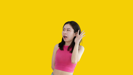 Asian woman eavesdropping or overhearing secret conversation isolated on yellow background, Gossip,...