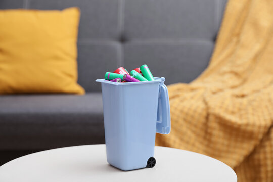 Mini recycling bin with different types of batteries on white table indoors