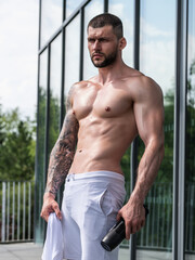 Obraz premium Muscular hunk with posing in gym. Fitness male model near gym equipment. Young muscular man workout. Sport man with strong muscular torso in gym. Sport and motivation. Exercises with weight.