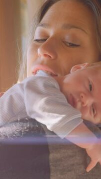 Animation of glowing spots over happy caucasian mother with sleeping baby