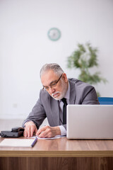 Old male employee working in the office