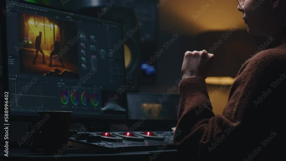 Poster female video maker works in studio on computer, uses color grading control panel. the colorist edits