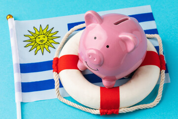 Piggy bank, lifebuoy and flag on a blue background, the concept of saving the Uruguayan economy