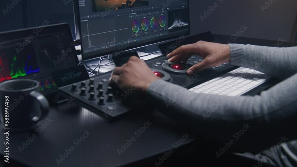 Poster hands close up of african american video editor working by color grading control panel in studio wit