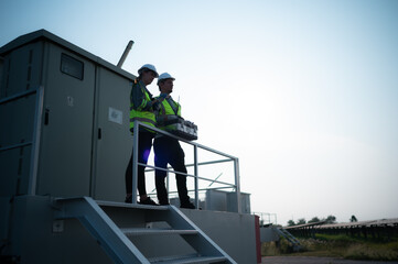 A team of electrical engineers inspecting solar panels in a hundred acre field, in the evening...