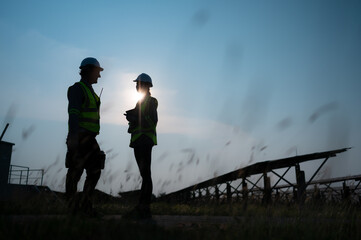 A team of electrical engineers inspecting solar panels in a hundred acre field, in the evening after completing the daily work tasks with the setting sun.