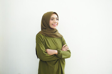 Smiling young Asian Muslim woman wearing green casual dress and headscarf feels confident and joyful isolated over white background. Ramadan Concept.