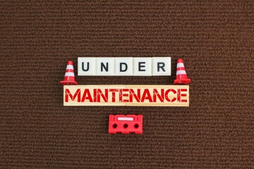 construction cones and alphabet letters with the word under maintenance. concepts in maintenance