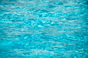 Background of blue water in swimming pool with sun reflection, ripple water wave in pool. Clear water background.