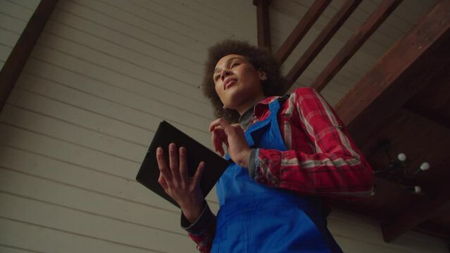 Low angle view of creative attractive African American women in workwear networking on digital tablet, planning home renovation project while preparing for redesign and apartment improvement.
